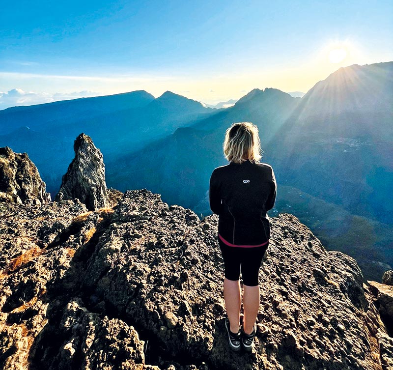 Emma est une fan de randonnée. Elle est ici au piton du Maïdo à La Réunion, admirant le lever du soleil.