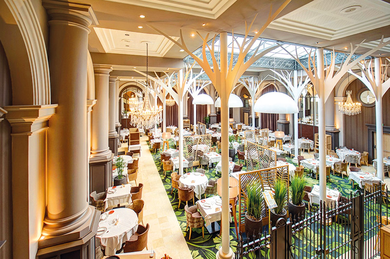 Situé dans le jardin d’hiver, le restaurant La Verrière se décline dans une ambiance bucolique. Un mur végétal et une fontaine longeant l’escalier guident les convives vers une belle salle ponctuée de claustras évoquant des cloisons de feuillages. 60 000 couverts sont servis par an à La Verrière qui dispose de sa propre cuisine et de sa brigade dédiée.