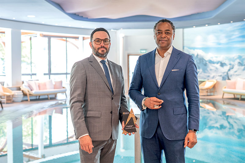 Marc Figueiredo, directeur général de l’Hôtel Royal, et Patrick Saussay, directeur général de Global Project & Spa Advisory, posent devant la piscine intérieure de l’evian®SPA, avec l’Award du Meilleur Espace Wellness, qu'ils ont reçu lors du dernier salon Hotel & Restaurant Meetings. © E.Guibaud